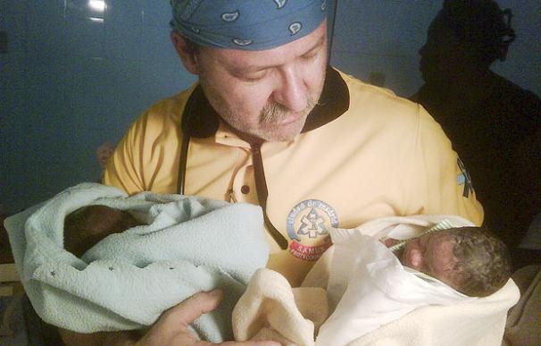 Un sanitario coge entre sus manos a dos mellizos haitianos - EFE