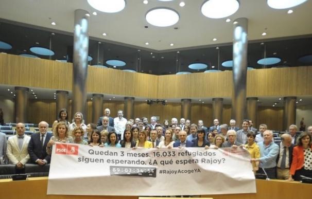 Diputados del PSOE despliegan una pancarta en el Congreso para recordar el compromiso de acogida de refugiados de España