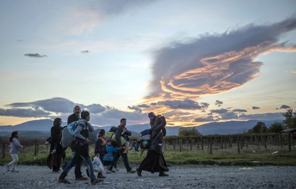 Migrants and refugees walk to catch a bus to Serbi