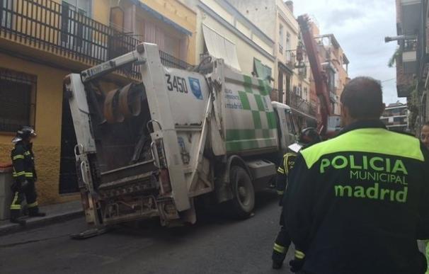 Bomberos retiran un camión de basura atrapado en un socavón de Vallecas