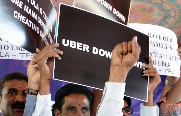 Indian Uber taxi drivers display placards and shou
