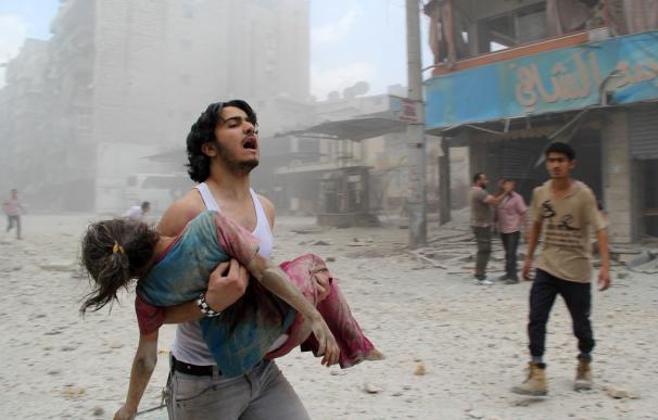 Un joven lleva en brazos a una niña que ha sido herida en un ataque de las fuerzas gubernamentales sirias en el distrito de Kallaseh, Alepo.