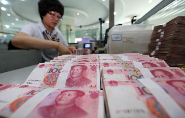A teller counts yuan banknotes in a bank in Lianyu
