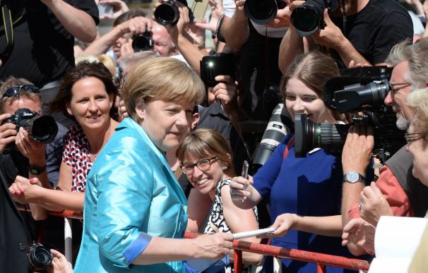 German Chancellor Angela Merkel (C) signs autograp