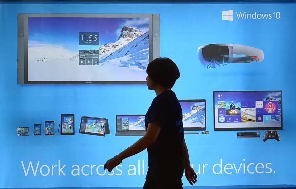 A woman walks past a billboard for Windows 10, the