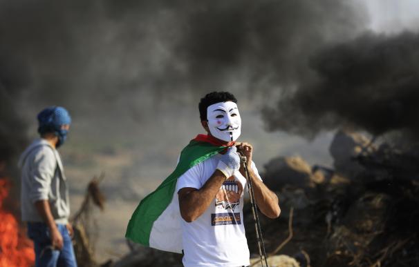 A masked Palestinian protester clashes with Israel