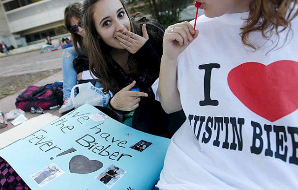 Unas jóvenes adolescentes muestran pancartas, camisetas y objectos con la efigie de su cantante preferido