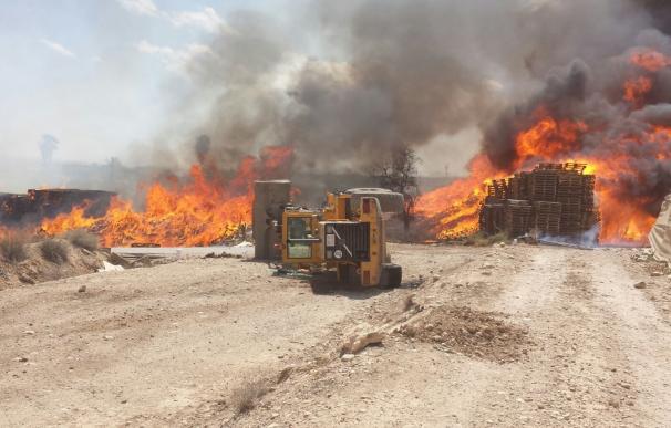 Helicóptero de la DGSCyE y bomberos trabajan en la extinción de un incendio en una granja de Totana