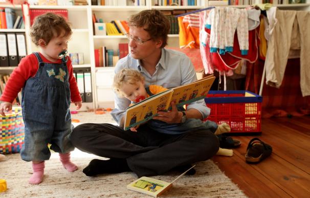 Un padre le lee cuentos a sus hijos mellizos