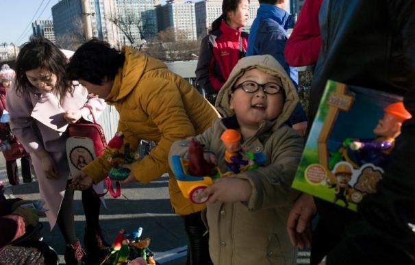 Un niño muestra un juguete a su madre en Beijing el 10 de febrero de 2017 (AFP PHOTO / Fred DUFOUR)