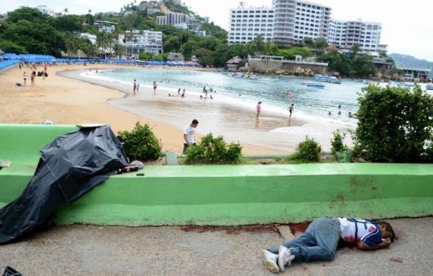 Mientras unos se bañan en Acapulco, un niño yace muerto a tiros, junto a otro cadáver.