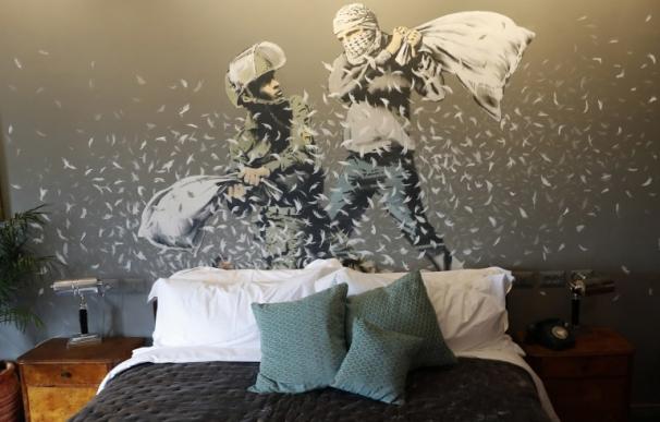La cama y un mural dentro del hotel abierto por Banksy junto al muro israelí (THOMAS COEX / AFP)