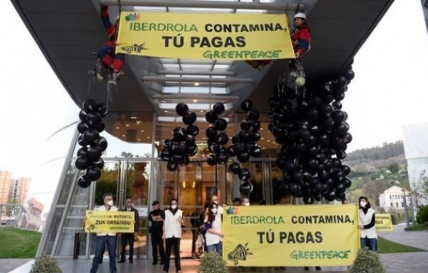 Activistas de Greenpeace despliegan pancartas en la sede de las eléctricas en Madrid