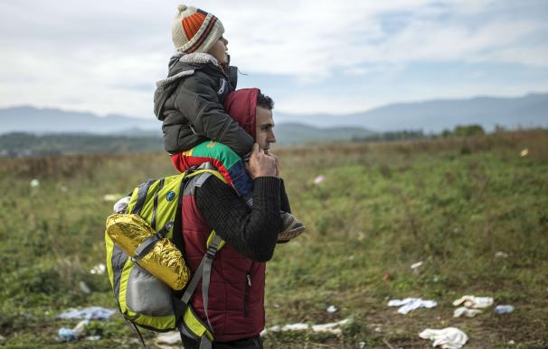 Un hombre lleva a su hijo a hombros / AFP