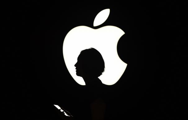 A reporter walks by an Apple logo during a media e