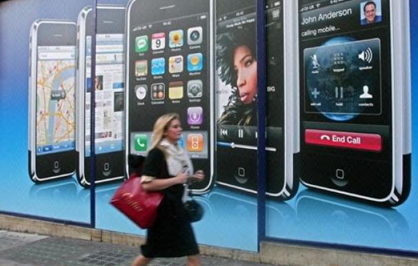 Una mujer pasea por delante de un cártel de iPhone