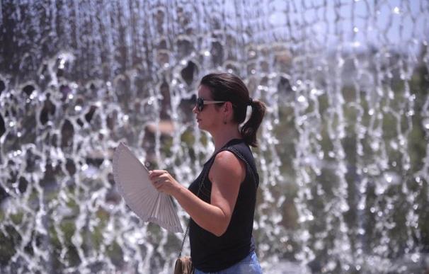 Una joven se abanica mientras pasa junto a una fuente del centro de Córdoba, hoy en el que aún se mantiene activada la alerta por calor en riesgo extremo. EFE/Rafa Alcaide