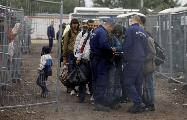 La policía registra a los refugiaos que llegan a un campo en la frontera