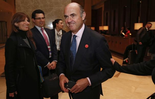 Spain's Economy Minister Luis de Guindos (C) walks