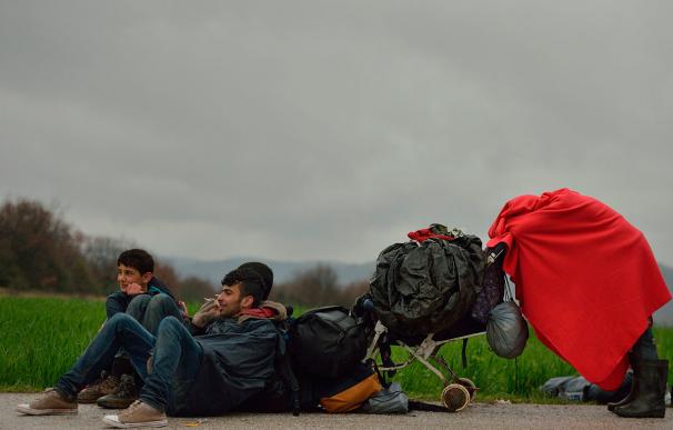Un niño refugiado se cubre una manta roja mientras descansan cerca del campo de Idomeni, en la frontera de Grecia y Macedonia el 15 de marzo