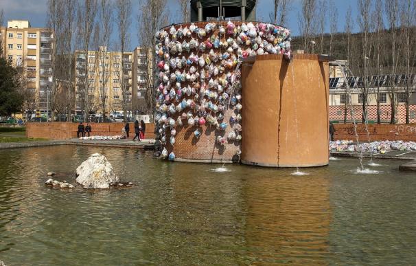 Un centenar de guirnaldas de bolsas de plástico decoran la fuente del Parque del Mundo de Pamplona