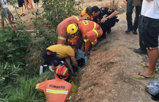 Los bomberos desvían el agua de una acequia en Rafelguaraf para rescatar a una anciana