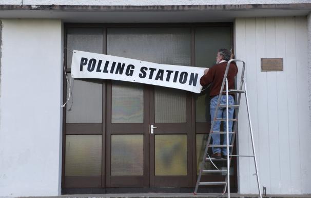 Un trabajador coloca el cartel de "colegio electoral" en el Colegio Nacional de Doolargy en Ravensdale (Irlanda)