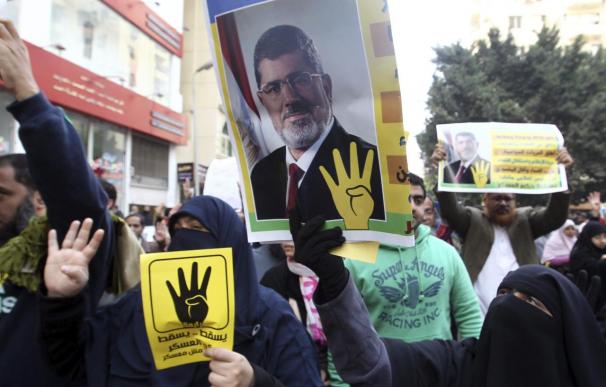 Simpatizantes del depuesto presidente egipcio Mohamed Mursi muestran retratos del exmandatario y el "saludo de cuatro dedos" durante una manifestación convocada en El Cairo.