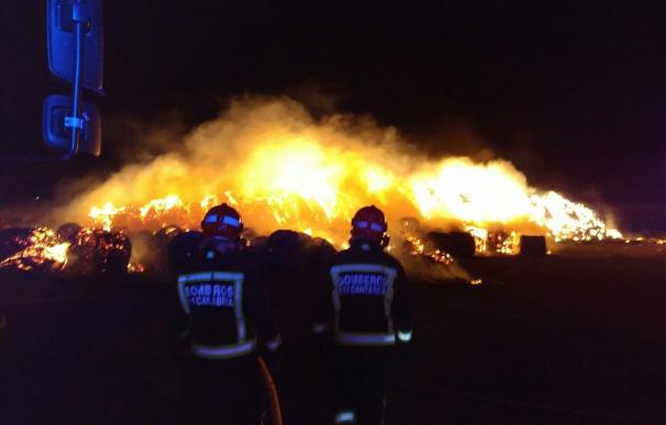 Bomberos del 112 trabajan en la extinción de un incendio en una pila de 1.500 pacas en Requejo