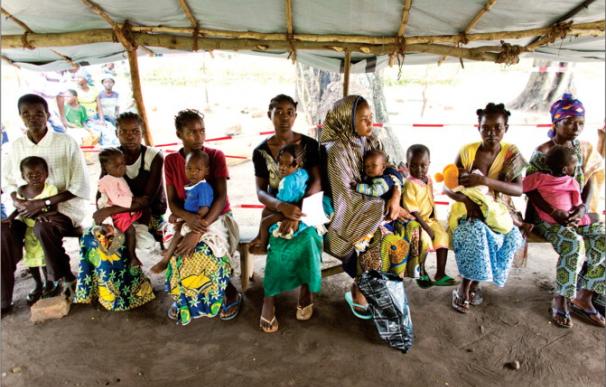 Un grupo de mujeres espera asistencia sanitaria con sus hijos en un país africano