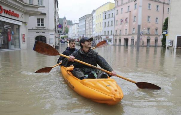 Dos hombres montados en una barca hinchable navegan en una calle inundada de la ciudad de Passau, en Alemania