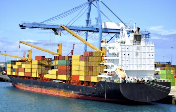 Un barco mercante recibe contenedores para ser transportados.