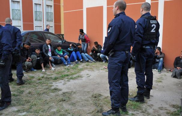 Policías vigilan a varios de los 51 inmigrantes tunecinos llegados de Italia que fueron arrestados por la Policía Nacional francesa.