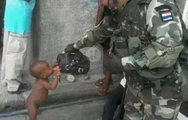 Un soldado paraguayo da de beber a un niño desnudo en Haití