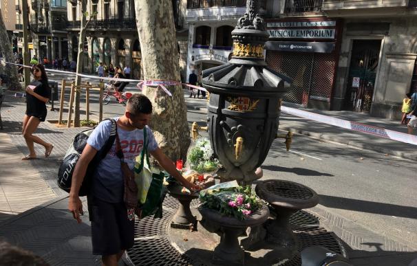 Un joven coloca flores en el lugar donde falleció una persona, esta mañana, en Las Ramblas.