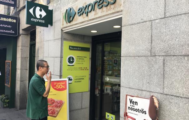 Ángel fuma en la puerta de su Carrefour Express, en la Plaza del Ángel de Madrid.