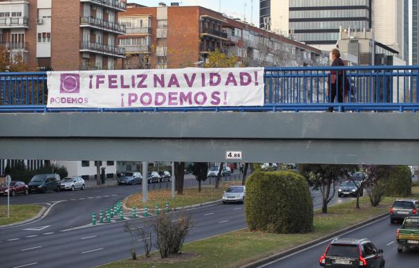 El partido Podemos felicita la Navidad a los madrileños con un cartel colocado en una pasarela del Paseo de la Castellana