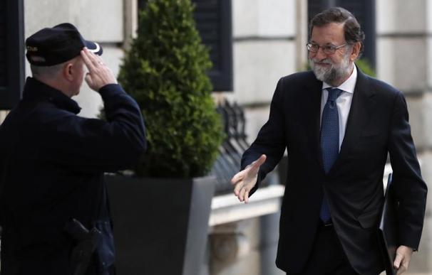 El presidente del Gobierno, Mariano Rajoy, saluda a un policía a la entrada del Congreso de los Diputados