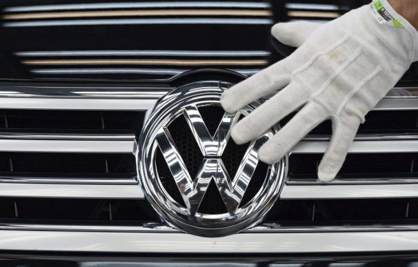 La mano de un empleado mientras toca el logotipo de Volkswagen en la planta de la compañía en Dresde (Alemania). (Ralf Hirschberger / EFE)