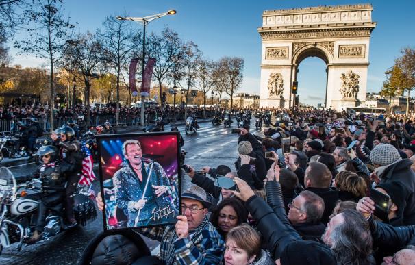 Un fan sostiene un póster del cantante francés Johnny Hallyday durante su procesión fúnebre en los Campos Elíseos en París, Francia, el 9 de diciembre de 2017 ( EPA/CHRISTOPHE PETIT TESSON)