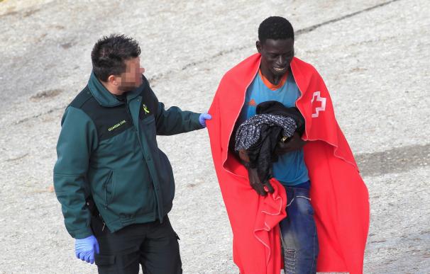 Un agente de la Guardia Civil ayuda a uno de los tres inmigrantes rescatados hoy por Salvamento Marítimo cuando viajaban en una patera en aguas del Estrecho y que han sido trasladados al puerto de Tarifa (Cádiz). EFE/A.Carrasco Ragel