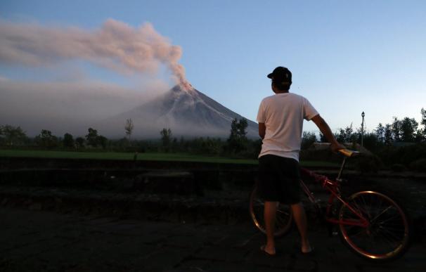 Un hombre observa el volcán Mayon mientras entra en erupción