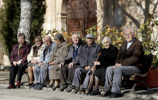Varios ancianos toman el sol en unos bancos de Olmeda de la Cuesta, Cuenca (EFE/Santiago Torralba)