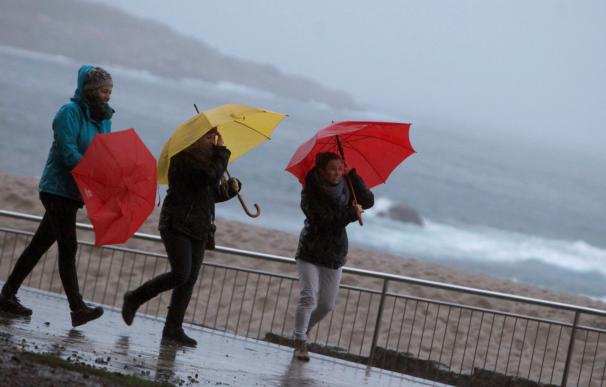 Tres mujeres se protegen de la lluvia en el paseo marítimo de A Coruña (EFE/Cabalar)