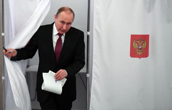 El candidato y actual presidente de Rusia, Vladimir Putin, abandona la cabina de voto en su colegio electoral, hoy 18 de marzo en Moscú