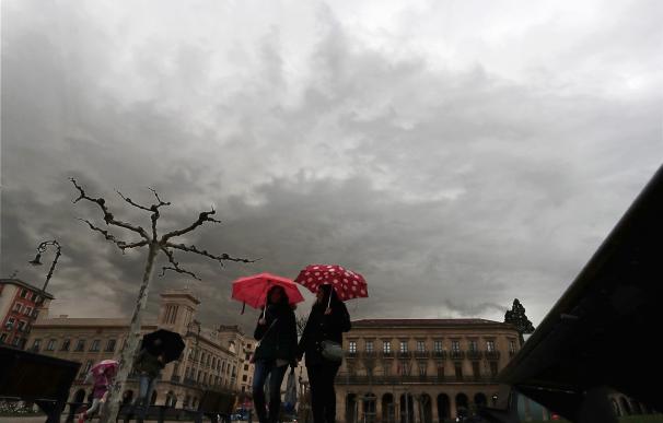 Dos personas se protegen del agua con un paraguas en la Plaza del Castillo de Pamplona (EFE/Jesús Diges)