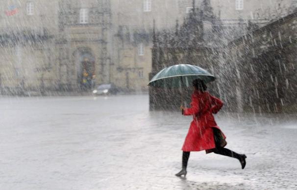 Una mujer cruza la plaza del Obradoiro, en Santiago de Compostela, donde ha caído una fuerte tormenta. (Imagen de archivo) / Xoan Rey (EFE)