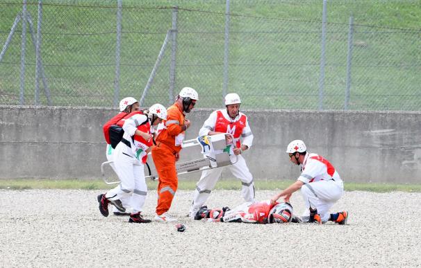 El piloto de prueba del equipo de Moto GP Ducati Michele Pirro (en el suelo) recibe atención médica tras sufrir un accidente en Mugello (EFE/ Claudio Giovannini)