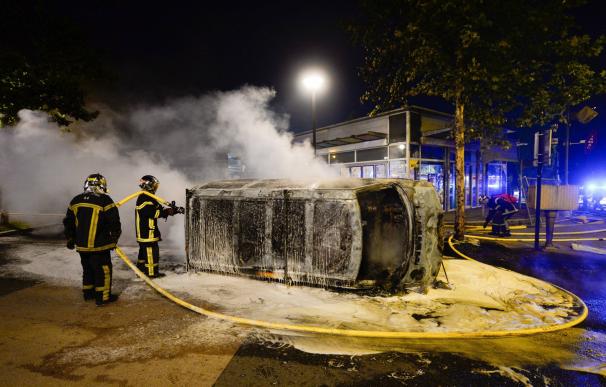 Bomberos trabajan en la extinción de un incendio en un vehículo durante unos disturbios en Nantes (Francia) el 3 de julio de 2018 (EFE/ Franck Dubray)