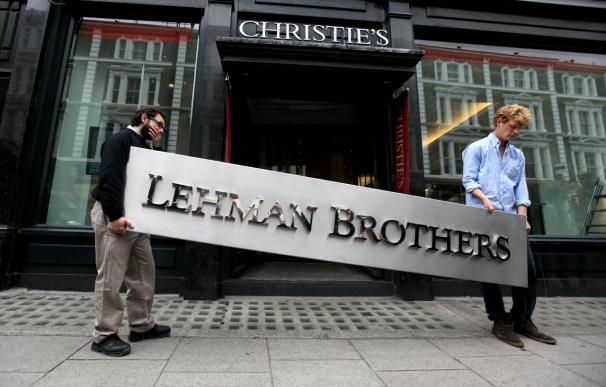 Dos empleados portan el logo Lehman Brothers para subastar sus obras de arte.